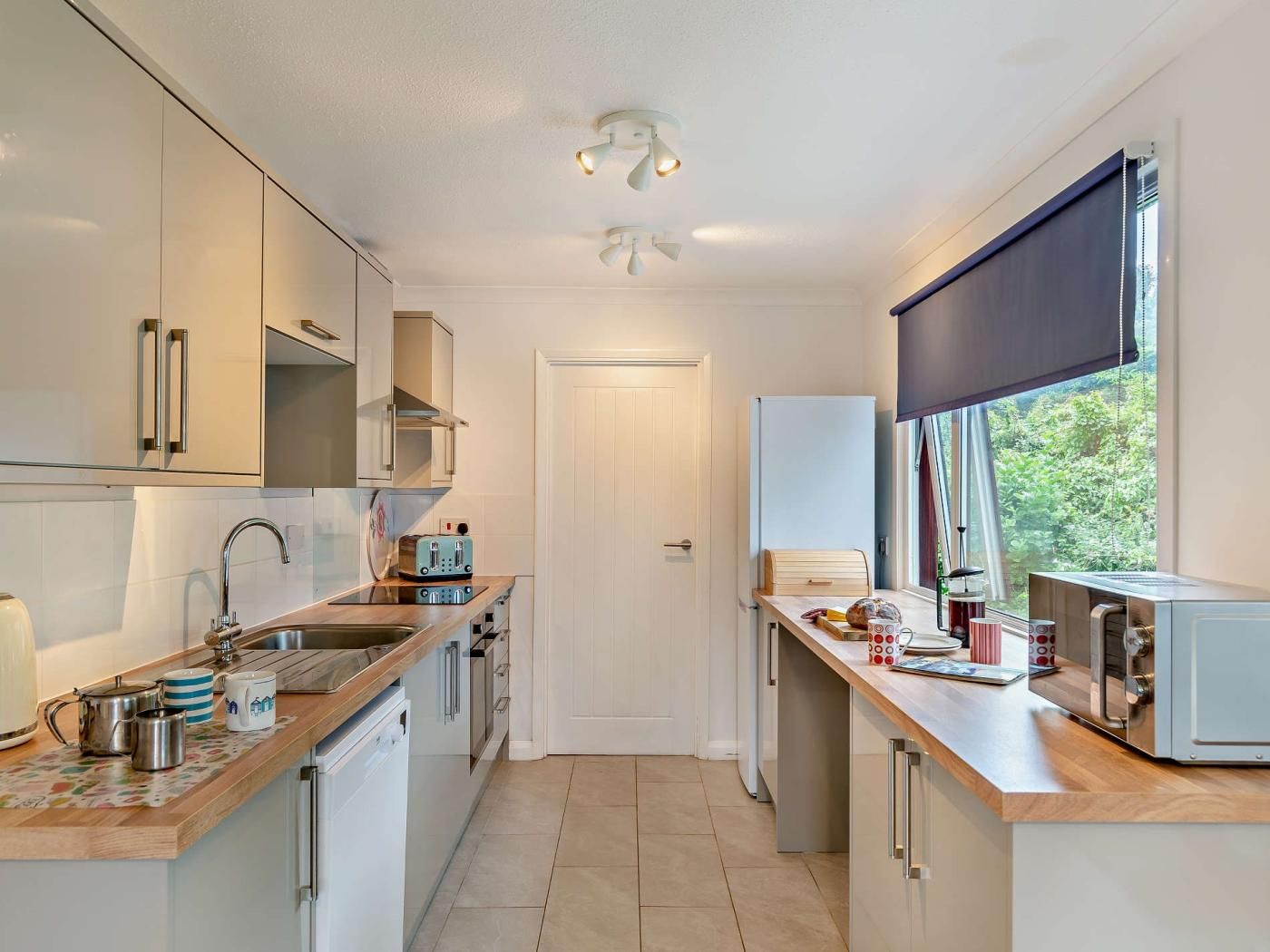 A compact kitchen with a sink, toaster, and a window with a view of greenery.