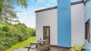 A small patio with a table and chairs, a door, and a window. - 2 Bed in Saltash (oc-95642) (Notter)