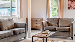 Ein Zimmer mit zwei Sofas, einem Couchtisch und einem Holzschrank.