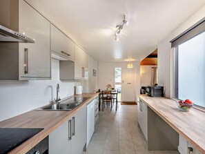 Eine moderne Küche mit einer Kochinsel, einem Essbereich mit Tisch und Stühlen sowie einem Fernseher in der Ecke.