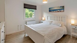 Ein Schlafzimmer mit Bett, Fenster mit Blick, Heizkörper und einem Bild an der Wand.