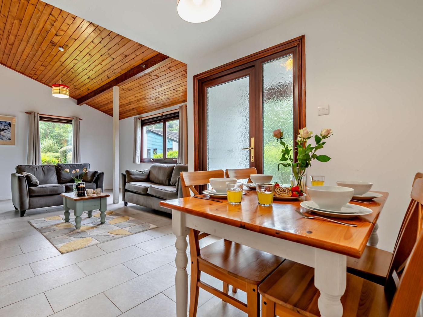 Uma sala de jantar com uma mesa de madeira, cadeiras e um vaso com flores.