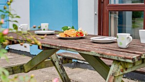 Een houten picknicktafel met borden, bekers en eten.