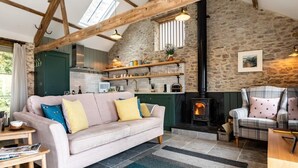 Ein gemütliches Wohnzimmer mit Steinwand, Kamin, Sofa und Holzboden.