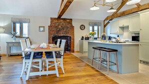A spacious kitchen with a central island, a dining area with a brick fireplace, and exposed wooden beams. - 1 Bed in Bromyard (oc-95609) (Pencombe)
