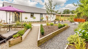 Una casa moderna con un patio, jardines y una pérgola.