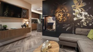 Een moderne woonkamer met een grote flatscreen-televisie, een houten salontafel, een bank en een decoratief behang.