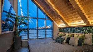 Een modern interieur met een groot raam, een houten plafond en een zithoek met kussens.