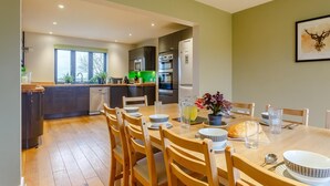 A modern kitchen with a dining area, wooden chairs, and a table set for four. - 5 Bed in Bideford (oc-76546) (Hartland)