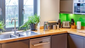 A modern kitchen with a sink, a kettle, a toaster, and a microwave. - 5 Bed in Bideford (oc-76546) (Hartland)