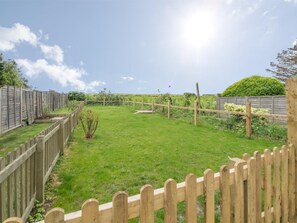 Ein umzäunter Garten mit Rasenfläche, Holzlattenzaun und einer Hecke.
