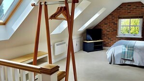 A room with a sloped ceiling, a loft bed, a wooden swing, and a view of the outdoors. - Countryside Garden Loft near Lymm (Warrington)