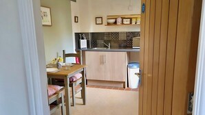A kitchen with a dining area, a tiled floor, and a wooden door. - Countryside Garden Loft near Lymm (Warrington)