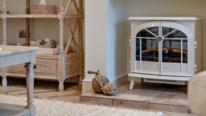 Una habitación con piso de madera, un armario blanco con puerta de vidrio y una silla de madera.