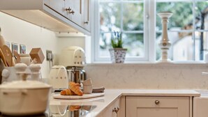 Una cocina con ventana, cafetera y un croissant en la encimera.