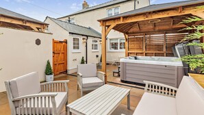 Un patio con mobiliario exterior, jacuzzi y una pérgola de madera.