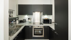 A modern kitchen with black cabinets, stainless steel appliances, a dishwasher, and a microwave. - Modern Flat with Balcony near Hackney Wick (London)