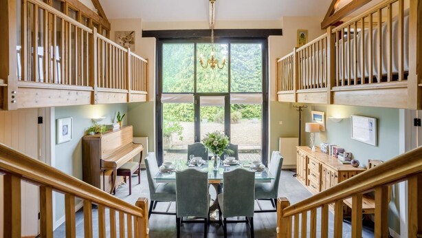 A dining area with a table set for four, flanked by wooden cabinets and a view of the outdoors through large windows. - 3 Bed in Shaftesbury (oc-95685) (Sedgehill)