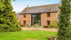 A brick house with a large glass door, a lawn, and a stone bench. - 3 Bed in Shaftesbury (oc-95685) (Sedgehill)