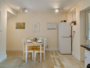 Una cocina funcional con una mesa de comedor, sillas, un refrigerador y una lavadora.