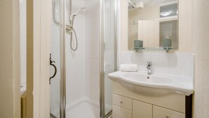 Ein Badezimmer mit Glasdusche, Waschbecken und einem Spiegel darüber sowie einem Handtuch auf dem Waschbecken.