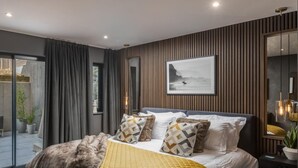 Ein modernes Schlafzimmer mit einem Bett, einem großen Fenster und Blick ins Freie.