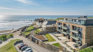 Ein Küstenhotel mit Steinaußenwand, mehreren Balkonen und Blick aufs Meer.