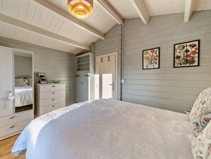A bedroom with a large bed, a wardrobe, a dresser, and two framed floral paintings on the wall.