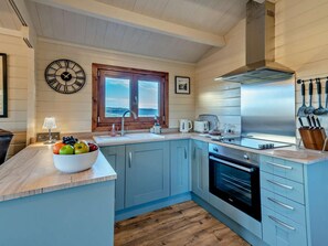 A modern kitchen with a wooden countertop, a built-in oven, and a window with a view. - 1 Bed in Kendal (oc-95745) (Crosthwaite and Lyth)