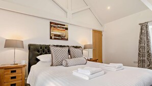 Un dormitorio con una cama grande, dos mesitas de noche, una puerta de madera y un cuadro en la pared.