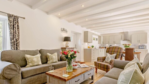Una sala de estar con un sofá, una mesa de centro y una cocina al fondo.