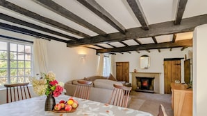 Una habitación acogedora con chimenea, una mesa de comedor con mantel floral y un sofá.