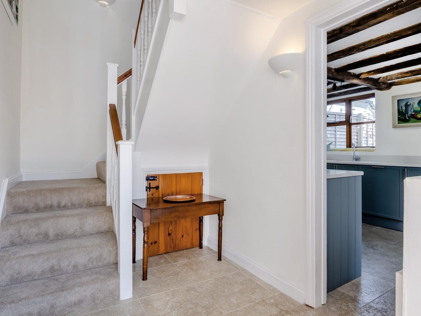 A staircase leading to a dining area with a wooden table and a view of a kitchen.