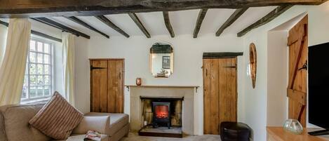 Una sala de estar acogedora con vigas de madera a la vista, una chimenea, un sofá y un televisor.