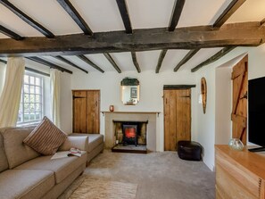 Una sala de estar acogedora con vigas de madera a la vista, una chimenea, un sofá y un televisor.