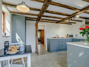 Eine Küche mit Holzbalkendecke, ein Essbereich mit Frühstückstisch und Blick in einen weiteren Raum.