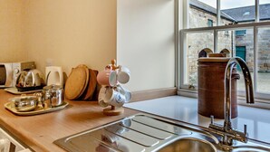 Eine Küche mit Spüle aus Edelstahl, einer Holzarbeitsplatte und einem Fenster mit Blick auf Steinbauten.