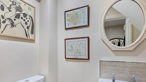 Ein Badezimmer mit Toilette, Waschbecken, zwei gerahmten Karten und einem Spiegel.