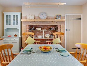 A dining area with a table set for two, a clock, and a shelf with kitchen items. - 1 Bed in Alnwick (oc-95776) (East Lilburn)