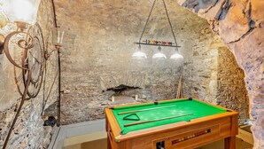 A billiards table in a room with a rustic stone wall, a clock, and hanging lights. - 4 Bed in Hawick (oc-95765) (Teviotdale)