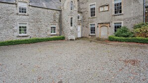 A stone building with a central tower, multiple windows, and a gravel courtyard. - 4 Bed in Hawick (oc-95765) (Teviotdale)