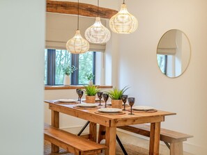 Ein Holztisch mit Tischsets, Weingläsern und Blumentöpfen.