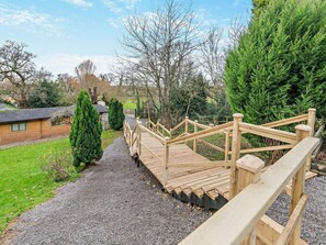 Eine Holzbrücke, die zu einem Haus mit einem Kiesweg führt.