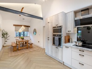 Eine moderne Küche mit eingebauten Geräten, ein Essbereich mit Holztisch und Bank sowie ein großer Spiegel an der Wand.