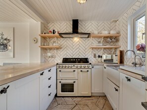 Eine moderne Küche mit einem Backsplash im Fischgrätmuster, einem schwarzen Herd und weißen Schränken.