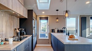 A modern kitchen with a central island, built-in appliances, and a skylight. - 2 Bed in Keswick (oc-95813) (Bassenthwaite)