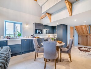 A modern kitchen with dark blue cabinets, a central island with seating, and a view of the outdoors through a window.