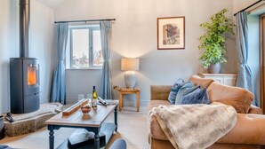 A cozy living room with a fireplace, a dining table, a sofa, and a potted plant. - 1 Bed in Gloucester (oc-95793) (Tirley)
