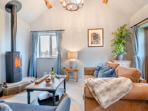 A cozy living room with a fireplace, a dining table, a sofa, and a potted plant. - 1 Bed in Gloucester (oc-95793) (Tirley)