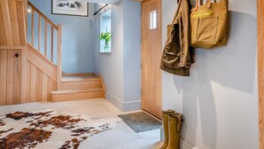 A staircase with wooden railings, a cowhide rug, a wooden door, and a wall-mounted coat rack with bags. - 1 Bed in Gloucester (oc-95793) (Tirley)